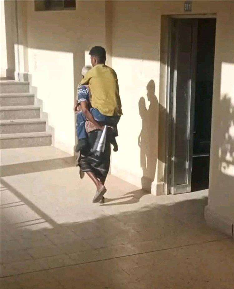 أب يمني يقطع المسافات يومياً حاملاً ابنه المعاق إلى الجامعة ويثير تعاطف الجميع